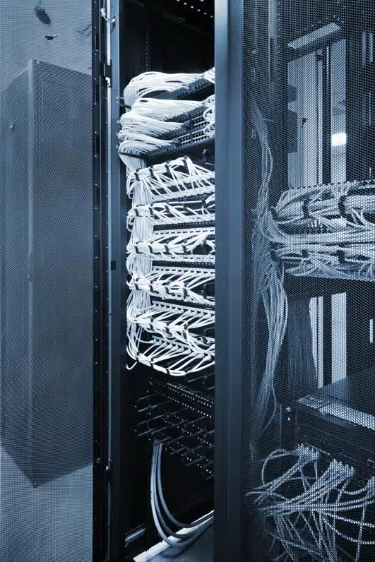 close-up view of network server racks filled with neatly organized white Ethernet cables in a data center. The scene is tinted blue, emphasizing the cool, controlled environment typical of high-tech infrastructure.